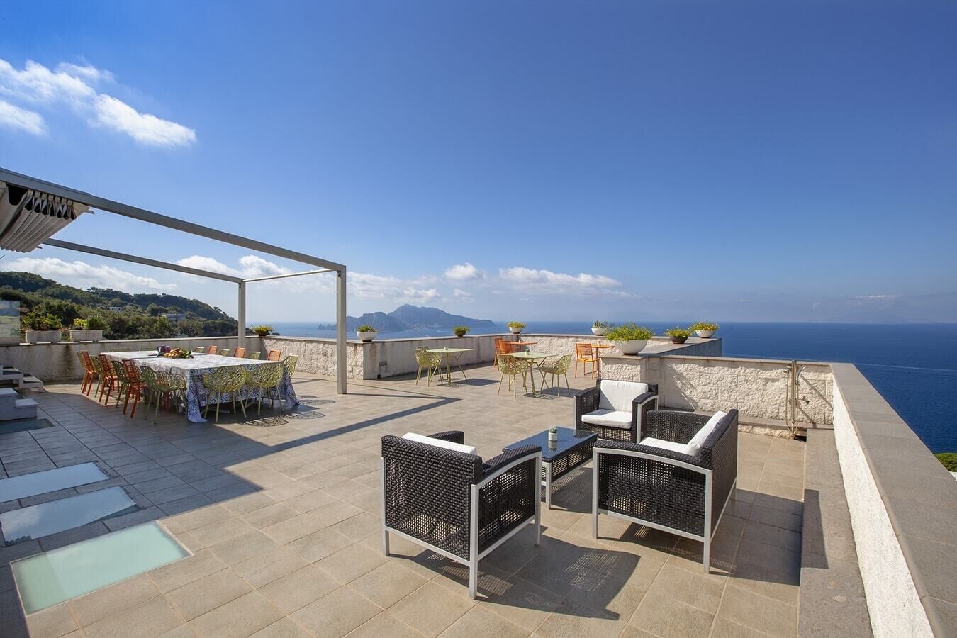 Una terraza en la azotea con zona de comedor, asientos exteriores y vista al mar.