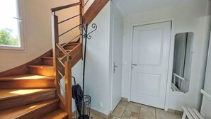 A wooden staircase with a metal railing, a white door, and a bench. - Nice apartment for 3 guests with WIFI and TV (Cancale)