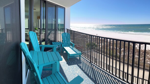 Un balcon avec des chaises turquoise donnant sur une plage.