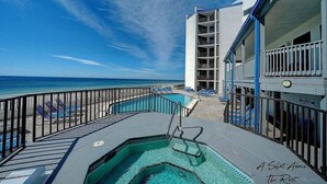 Un espace piscine avec vue sur l’océan, un escalier menant à un balcon et un immeuble à étages multiples doté de balcons.