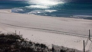 Une plage avec un ciel dégagé et la lumière du soleil se reflétant sur l’eau.