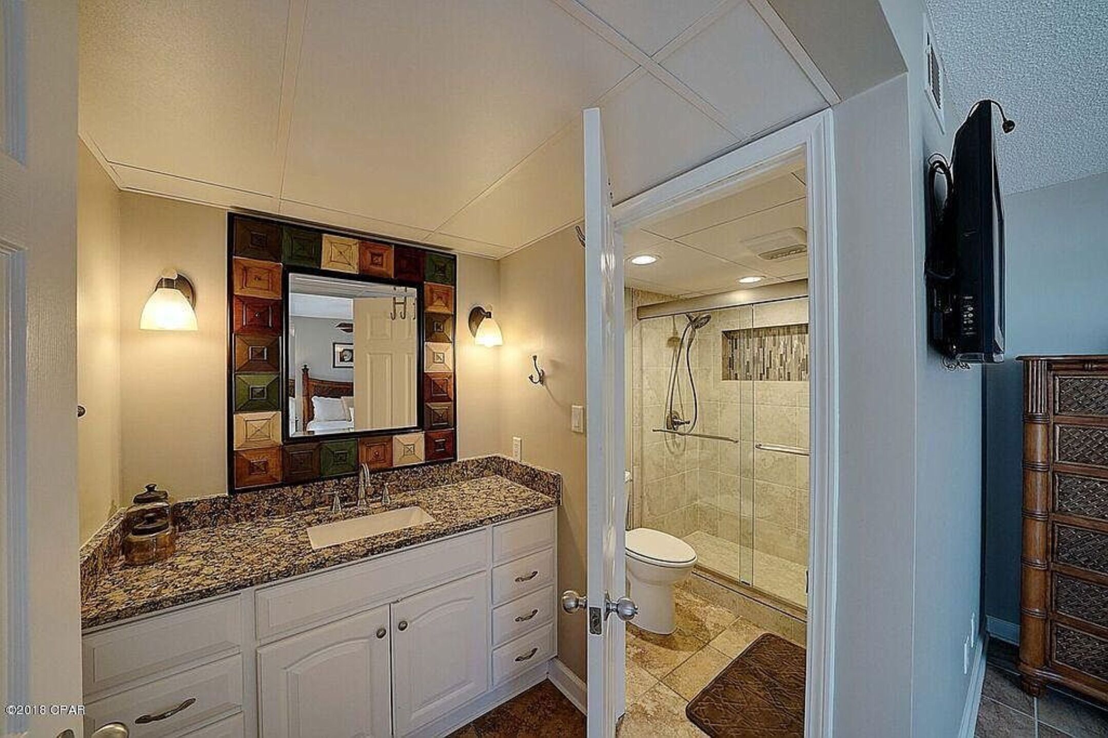 A bathroom with a large mirror, a sink, and a shower area.