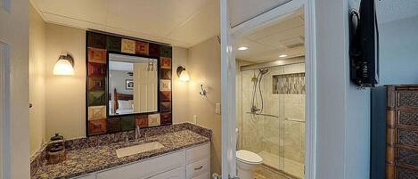 A bathroom with a large mirror, a sink, and a shower area.