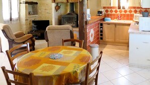 A cozy living room with a fireplace, a dining table with chairs, and a kitchen area with a sink and cabinets. - Wonderful private villa for 4 guests with TV, terrace and pets allowed (Labastide-de-penne)