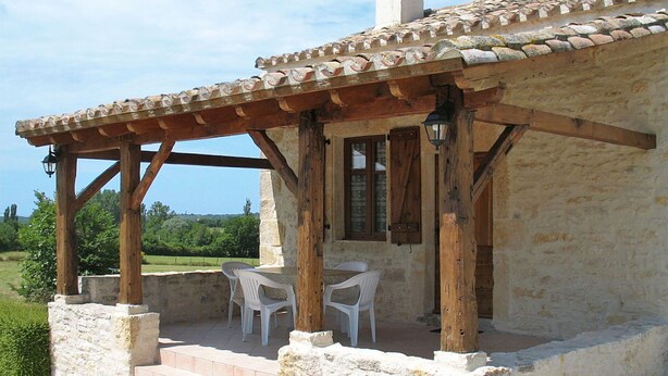 A rustic stone building with a wooden pergola, two white plastic chairs, and a view of the countryside. - Wonderful private villa for 4 guests with TV, terrace and pets allowed (Labastide-de-penne)