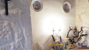 A rustic interior with a stone wall, a decorative vase with flowers, and a small shelf with a basket. - Wonderful private villa for 4 guests with TV, terrace and pets allowed (Labastide-de-penne)