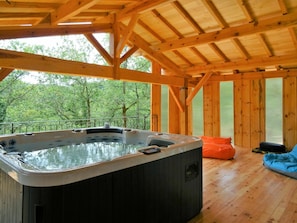 Une cabane en bois dotée d’un bain à remous, de planchers en bois et offrant une vue sur la forêt.