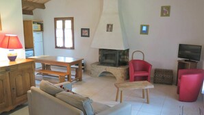 A living room with a sofa, a red chair, a wooden table, a television, and a fireplace. - Beautiful private villa for 4 people with private pool, WIFI, TV, terrace and pets allowed (Blanquefort-sur-briolance)