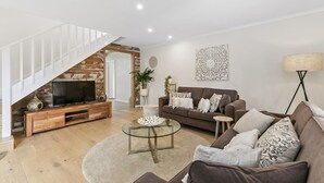 Een moderne woonkamer met een televisie, banken, een salontafel en een trap.
