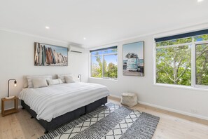 A bedroom with a bed, a nightstand, a lamp, a window, and artwork on the walls. - The Beach House Anglesea (Anglesea)