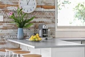 A kitchen counter with a coffee maker, a bowl of lemons, and a vase with flowers. - The Beach House Anglesea (Anglesea)
