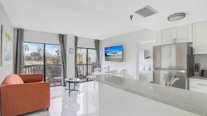 A modern kitchen with a large island, white cabinets, and a stainless steel refrigerator. - CLOSE TO UNIVERSAL and International drive, 2 bedroom king suite with parking (Orlando)