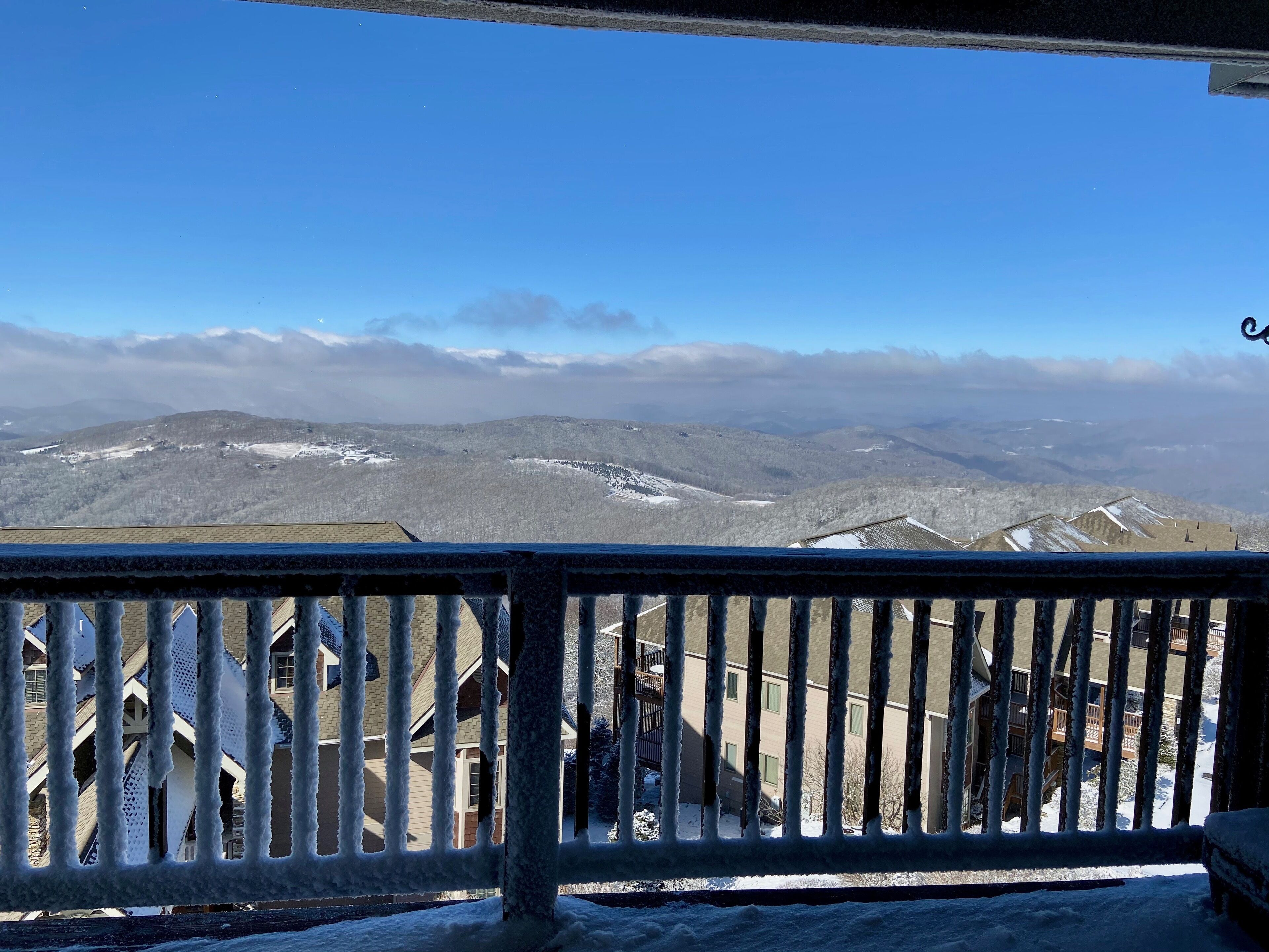 A balcony with a view of snow-covered mountains and a clear sky.