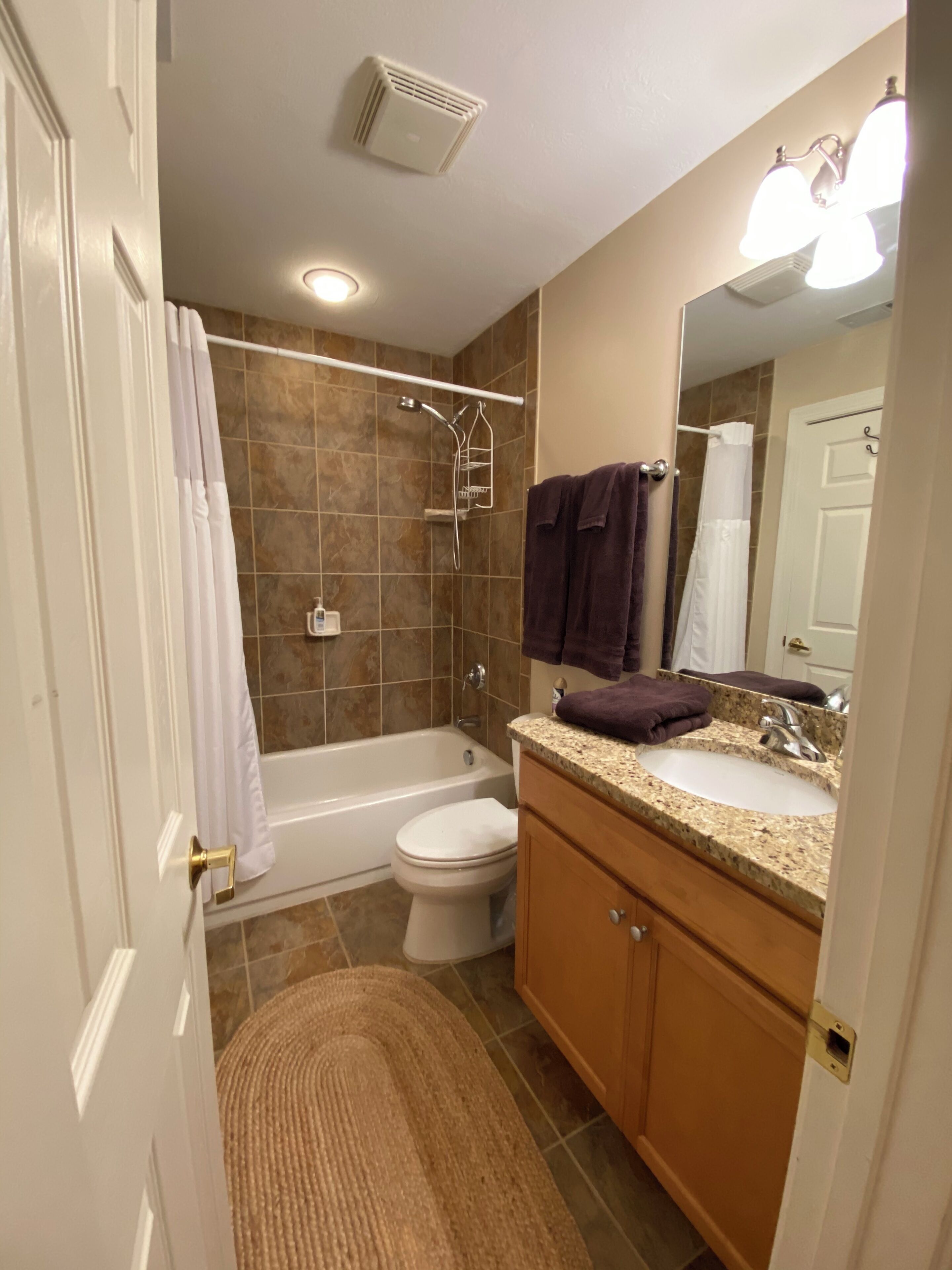 A bathroom with a bathtub, toilet, sink, and a shower area.
