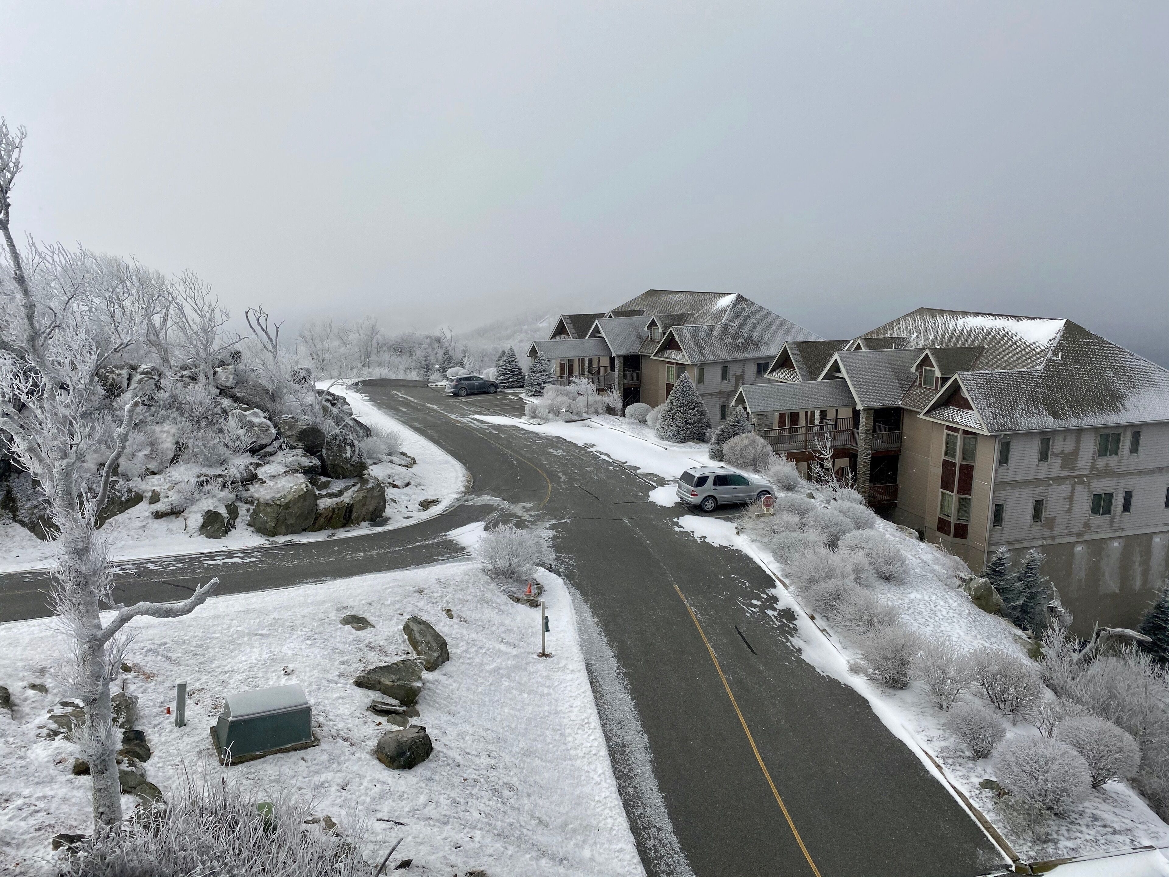 A residential area with snow-covered roads and houses, featuring a curved road layout and a mix of residential buildings.