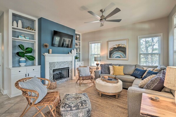 A living room with a fireplace, a sofa set, a television, and a ceiling fan. - Steps to Sand: Hilton Head Retreat w/ Pool Access! (Hilton Head Island)
