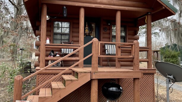 A wooden cabin with a porch, outdoor seating, a barbecue grill, and a satellite dish. - Once a Part of the Beloved Shady Oak Lodge - Cabin 3 w/ Boat Ramp (Many)