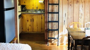 A rustic wooden cabin interior with a kitchenette, a dining area, and a ceiling fan. - Once a Part of the Beloved Shady Oak Lodge - Cabin 3 w/ Boat Ramp (Many)