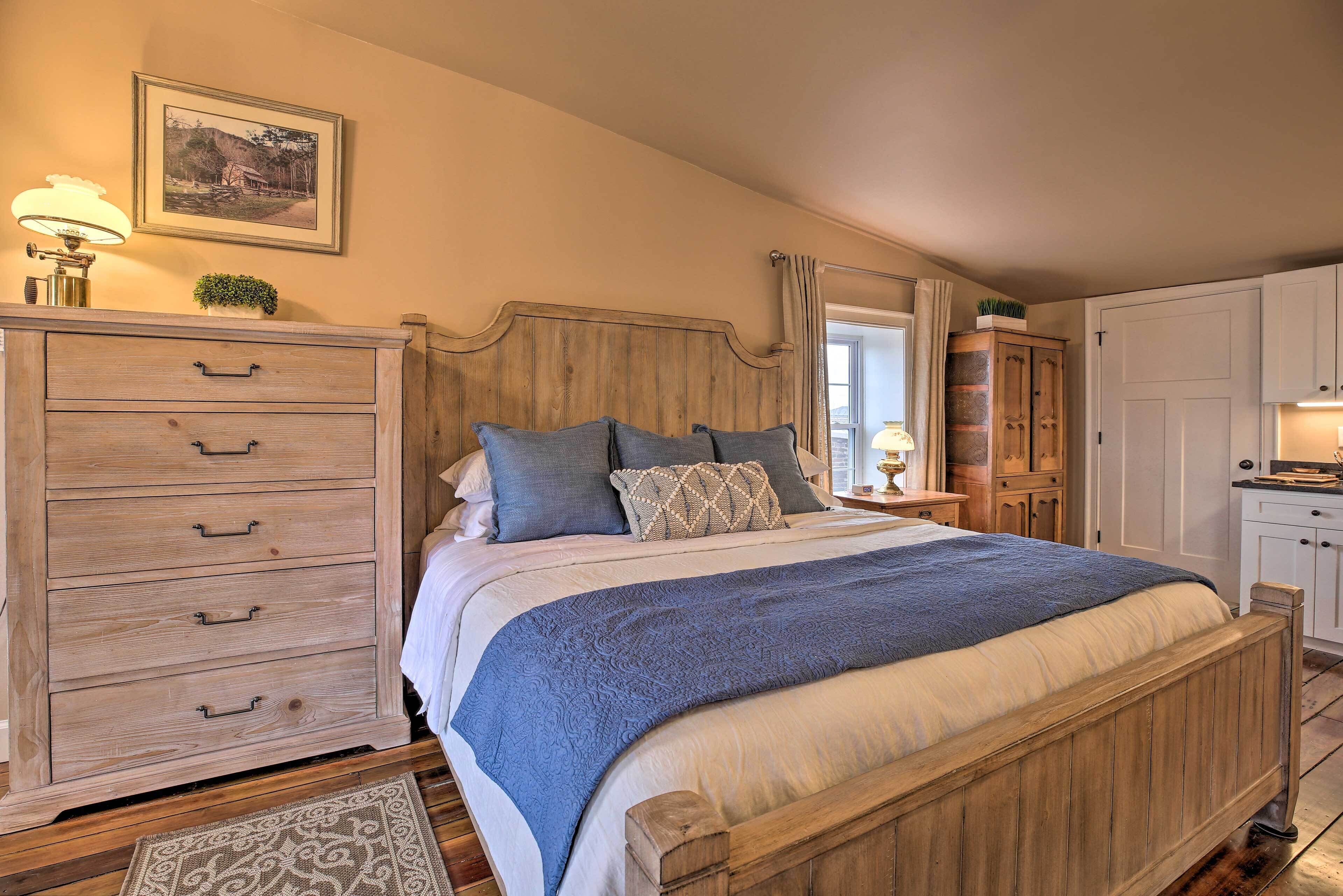 A bedroom with a wooden bed, a nightstand, a dresser, and a mirror.