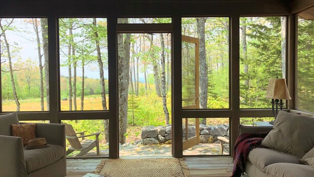 A spacious room with large windows, a sofa, a chair, and a small table. - Super-Private Dream House with Sunset Views (Sedgwick)