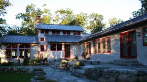 A two-story stone house with red-framed windows and a metal roof. - Super-Private Dream House with Sunset Views (Sedgwick)