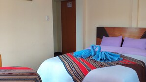 A hotel room with a bed, a wooden headboard, and a blue towel on the bed. - Habitaciones Confortables, Cama Extragrande (Huaraz)