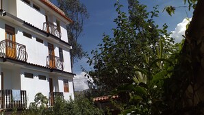 A multi-story building with balconies, surrounded by lush greenery. - Habitaciones Confortables, Cama Extragrande (Huaraz)
