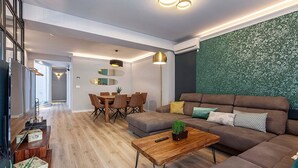 Un salon moderne avec un canapé marron, une table basse en bois et un coin repas comprenant une table et des chaises en bois.