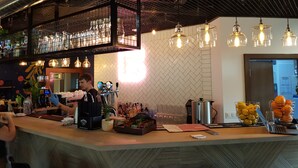 Zona de bar con mostrador, múltiples grifos y una variedad de botellas y vasos.
