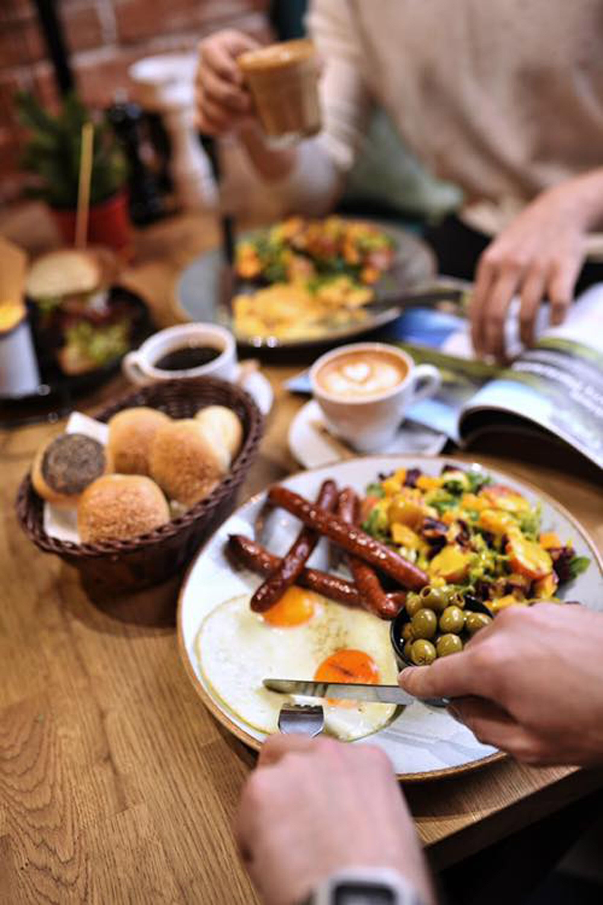 A dining table with various dishes, including sausages, eggs, and vegetables, and a cup of coffee.