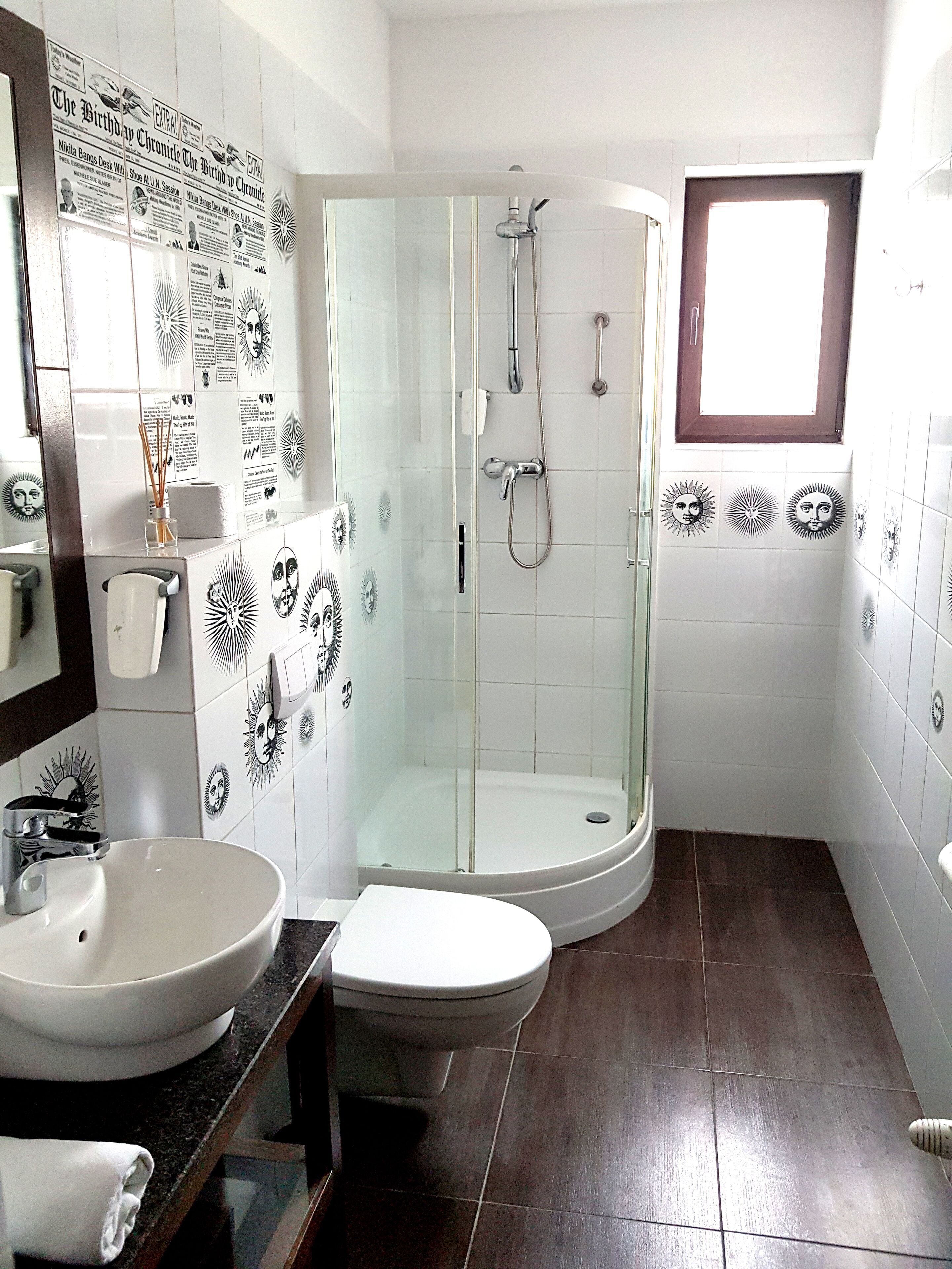 A bathroom with a glass-enclosed shower, a sink, and a toilet.