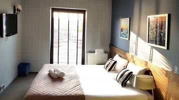 Une chambre d’hôtel avec un grand lit, une lampe de chevet, un téléviseur et une fenêtre avec des stores.