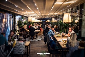 A restaurant with wooden tables and chairs, potted plants, and hanging lamps. - Hotel Willowa (Lublin)