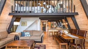 Een loft-achtige woonruimte met een hoge plafond, houten balken, een eethoek en een keuken.