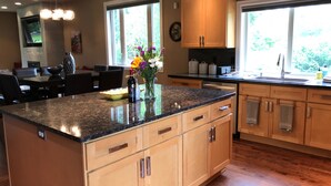 Una cocina con armarios de madera, encimera de granito y comedor con mesa y sillas.
