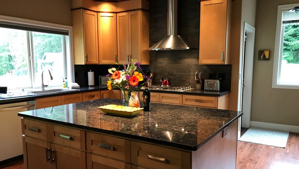Una cocina moderna con una isla central, armarios de madera y una campana extractora de acero inoxidable.