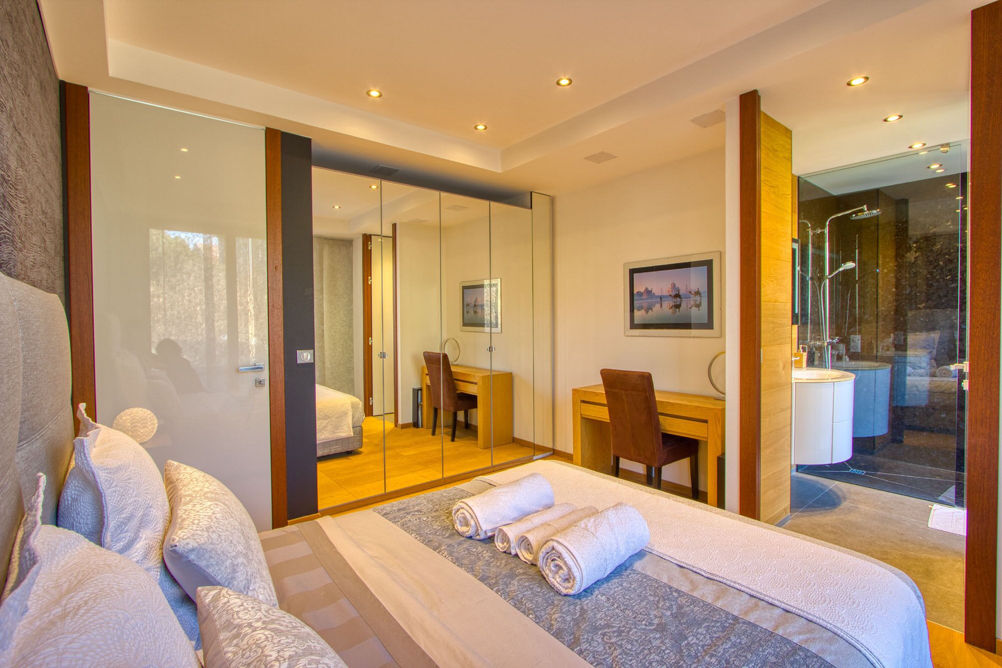 Une chambre d’hôtel moderne dotée d’un grand lit, d’un bureau, d’une chaise et d’une salle de bain avec une douche en verre.