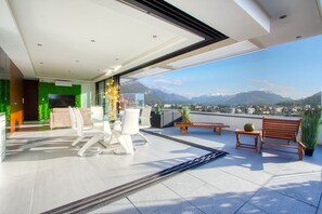 A modern balcony with a glass table and chairs, a wooden bench, and a view of mountains. - 180 ° Panoramic Lake and Mountains (Annecy)