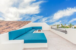 A rooftop terrace with a blue sofa, a small table, and a tiled roof. - Palmilla Dunes (San José del Cabo)