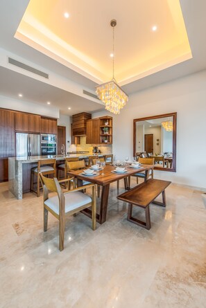 A modern kitchen with wooden cabinets, a central island, and a dining area with a wooden table and chairs.