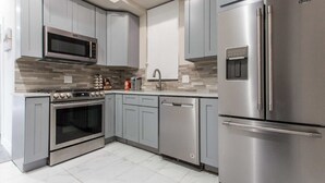 A modern kitchen with grey cabinets, stainless steel appliances, and a tiled backsplash.