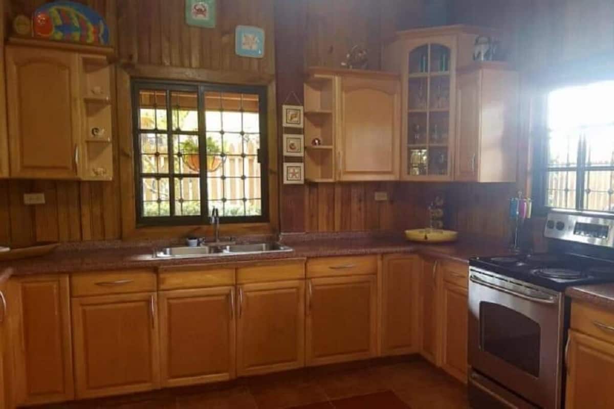 Cozinha com armários de madeira, fogão e janela com vista para o exterior.