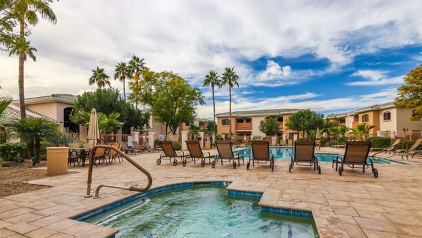 A pool area with lounge chairs and a small pool, surrounded by palm trees and buildings. - Ground Floor.Heated Pool! Hot Tub! Gas grill! 3 miles to Cardinal stad! 2 Kings! (Phoenix)