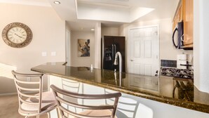 A modern kitchen with a central island, stainless steel appliances, and a decorative clock on the wall. - Ground Floor.Heated Pool! Hot Tub! Gas grill! 3 miles to Cardinal stad! 2 Kings! (Phoenix)