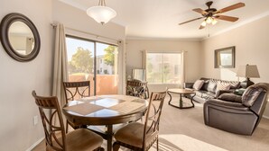 A spacious living room with a round dining table, comfortable seating, a ceiling fan, and large windows with blinds. - Ground Floor.Heated Pool! Hot Tub! Gas grill! 3 miles to Cardinal stad! 2 Kings! (Phoenix)