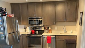 A modern kitchen with dark wood cabinets, stainless steel appliances, and a wooden dining table. - 207 Timbers Condominium (Crested Butte)