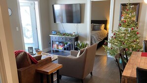 A living room with a flat-screen TV, a Christmas tree, a sofa, a coffee table, and a dining area with a wooden table and chairs. - 207 Timbers Condominium (Crested Butte)