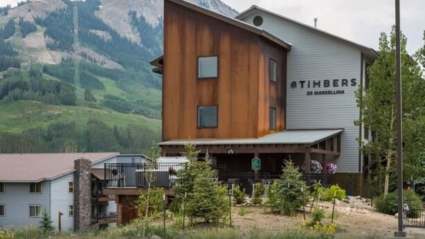 A modern building with a wooden facade and a sign reading "TIMBERS 20 MARCELLINA". - 207 Timbers Condominium (Crested Butte)