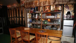 Un espace bar avec des chaises en bois, un comptoir et des étagères remplies de bouteilles et de verres.