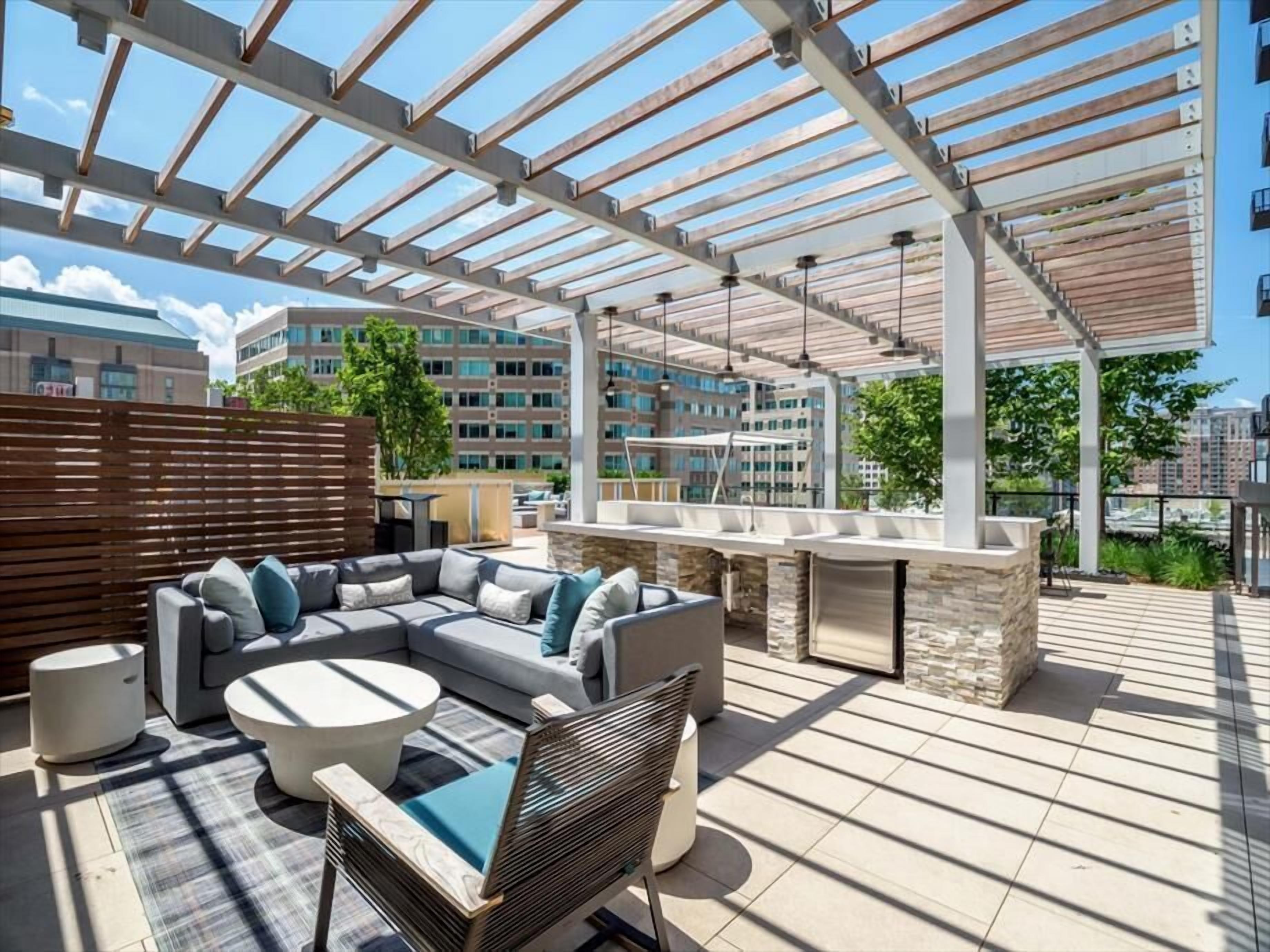Une terrasse extérieure dotée d’un espace salon abrité, d’une cheminée en pierre et offrant une vue sur le paysage urbain.